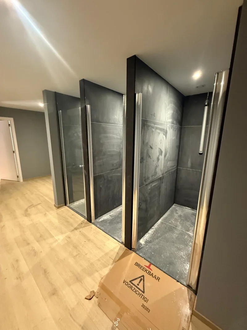 Visible dust and building residue on the walls and bases of several showers