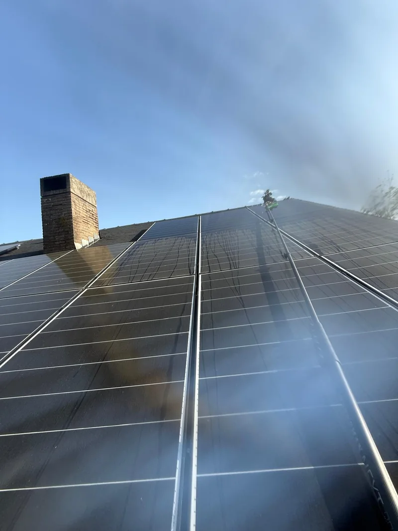 Cleaning rooftop solar panels with a brush and pole