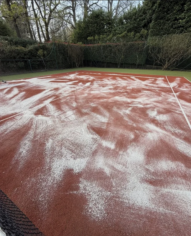 Tennis court treatment with cleaning product spread across the surface